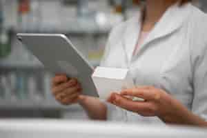 Foto gratuita farmacéutico femenino trabajando con tableta en la farmacia