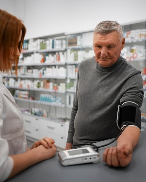 Foto gratuita farmacéutico de sexo femenino que controla la presión arterial del hombre mayor