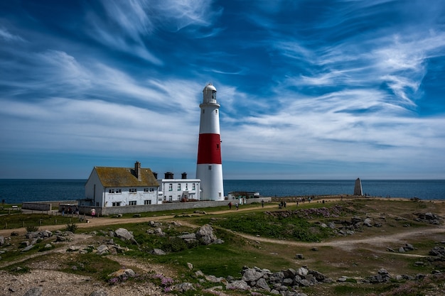 Faro blanco y rojo en la orilla cerca del mar bajo un cielo impresionante