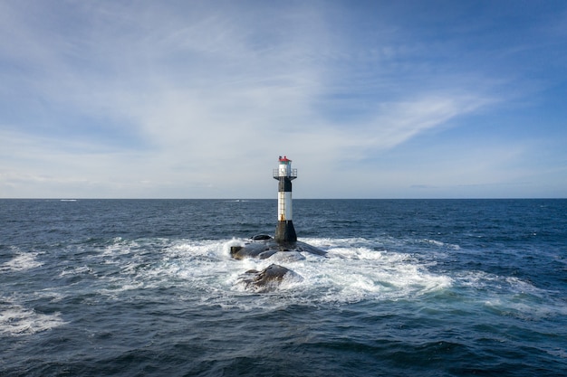 Faro en medio del mar bajo el cielo nublado