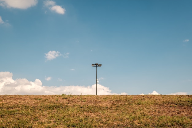 Foto gratuita farola en medio de un campo contra un cielo azul