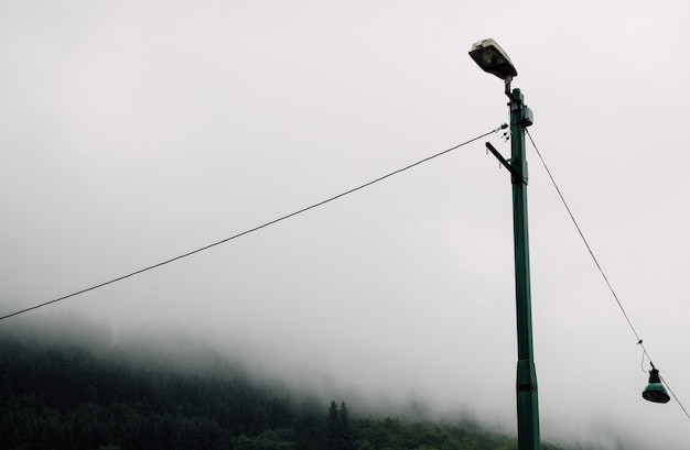 Farola de metal en el campo durante un brumoso día sombrío