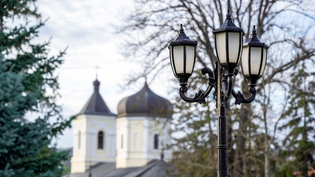 Farola vintage con la iglesia de piedra y árboles. Monasterio de Capriana, Moldavia