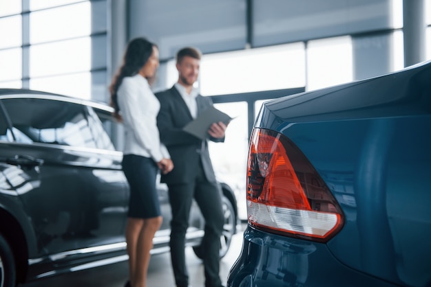 Faros traseros. Clienta y empresario barbudo con estilo moderno en el salón del automóvil