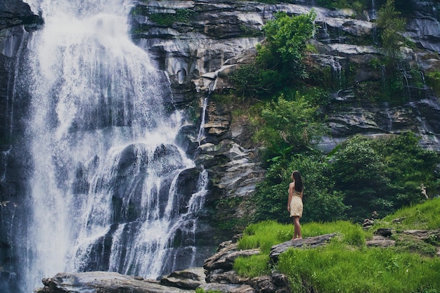 Fascinante disparo de ángulo bajo de una mujer admirando la cascada en el parque Doi Inthanon en Tailandia