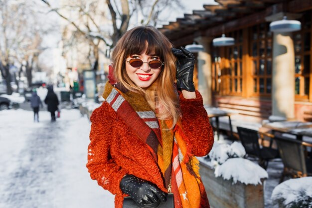 Fascinante mujer feliz en gafas retro posando al aire libre