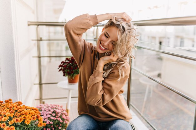 Fascinante niña caucásica sonriendo en la terraza. retrato de adorable dama rubia tiene un buen rato en fin de semana.