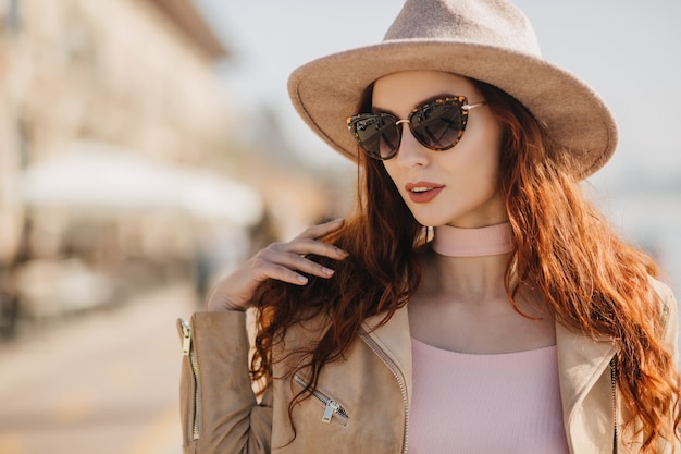 Fascinante señorita con peinado largo mirando a través de gafas de sol