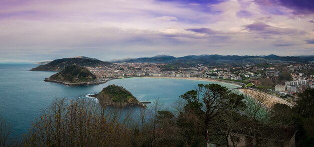 Fascinante vista de la ciudad a lo largo de la costa en un día nublado con una naturaleza exuberante