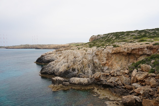 Fascinante vista de la costa de un océano con montañas rocosas bajo el cielo azul