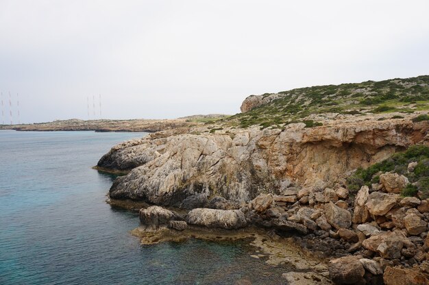 Fascinante vista de la costa de un océano con montañas rocosas bajo el cielo azul