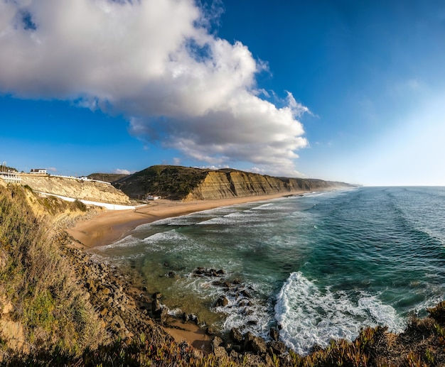 Fascinante vista de la costa rodeada de montañas rocosas bajo el cielo azul