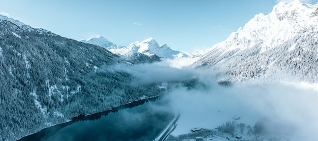 Fascinante vista de hermosos árboles cubiertos de nieve con un lago tranquilo bajo un cielo nublado