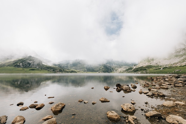 Fascinante vista de un lago en medio de montañas brumosas