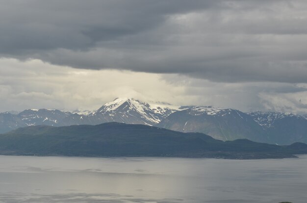 Fascinante vista de las montañas cubiertas de nieve detrás del lago en un día sombrío