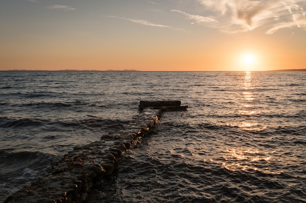 Fascinante vista del océano y un muelle bajo el colorido cielo durante la puesta de sol en Dalmacia, Croacia