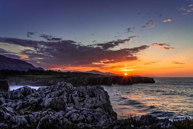 Fascinante vista del océano rodeado de montañas rocosas durante la puesta de sol