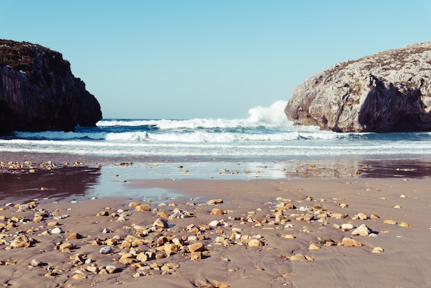 Foto gratuita fascinante vista de las olas del mar rompiendo en las rocas en un día claro