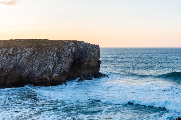 Fascinante vista de las olas del océano rompiendo en las rocas cerca de la playa en un día claro