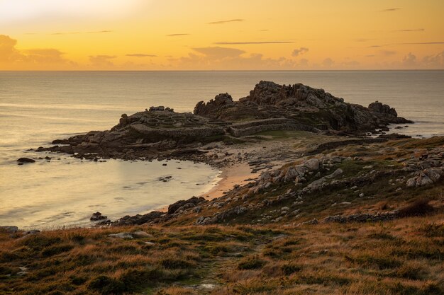 Fascinante vista de la orilla del océano en calma durante la puesta de sol en Galicia, España