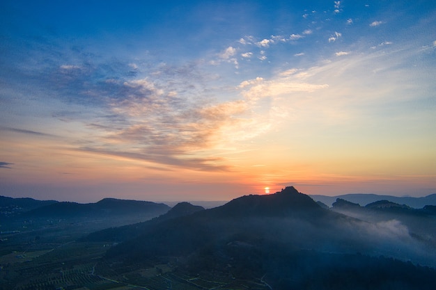 Fascinante vista de la puesta de sol naranja sobre las colinas y montañas