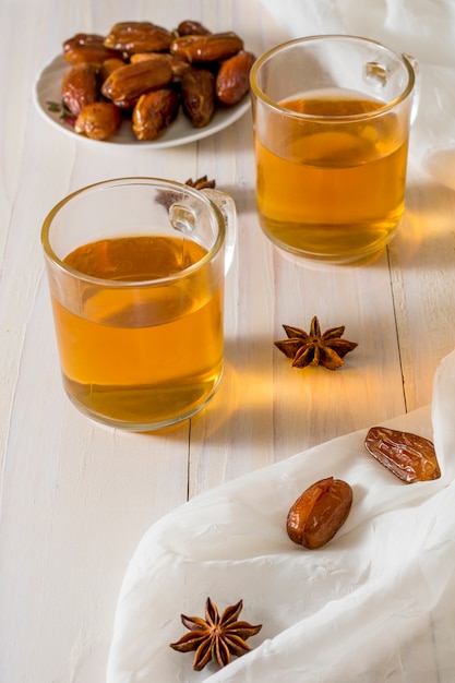 Fechas de frutas en plato con tazas de té.