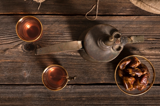 Fechas de frutas con vasos de té en la mesa de madera