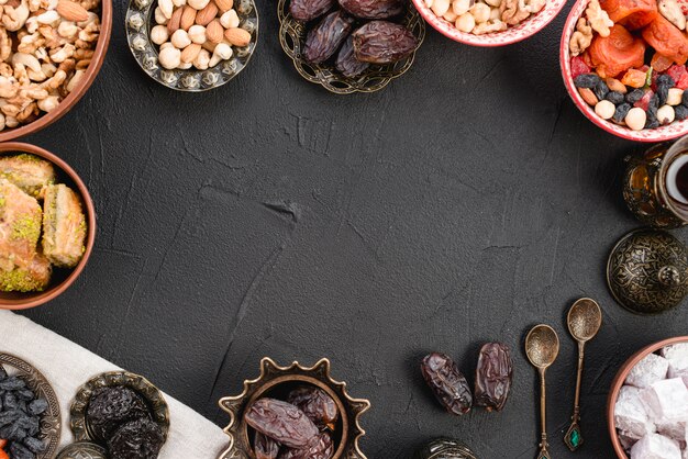 Fechas maduras jugosas; nueces; Lukum y baklava sobre fondo de hormigón negro