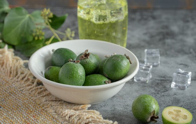 Feijoa fresca y vaso de limonada sobre fondo de mármol