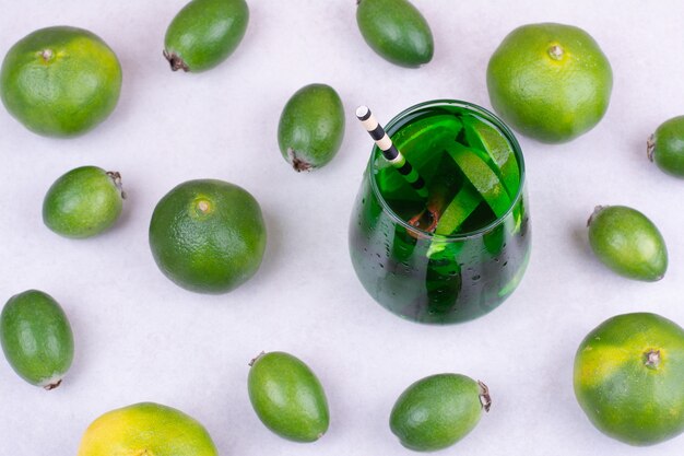 Feijoa y mandarinas con un vaso de jugo verde.