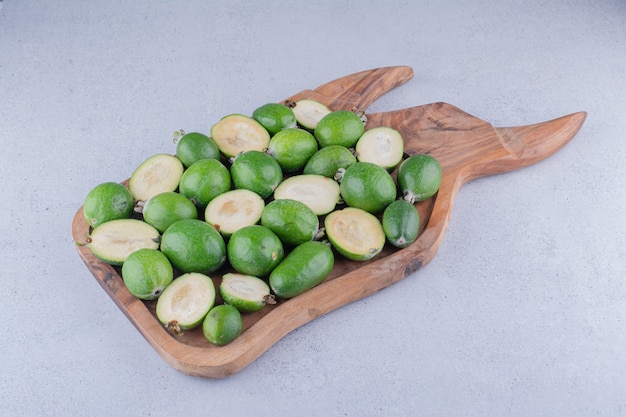 Feijoas envuelto en una bandeja de madera sobre fondo de mármol.