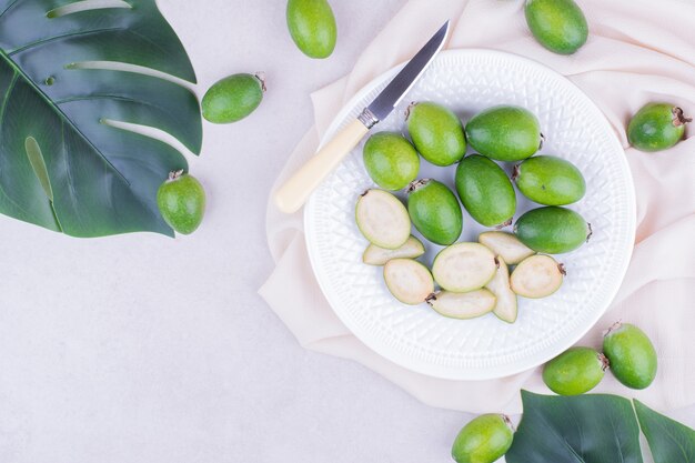 Feijoas en un plato blanco sobre superficie gris