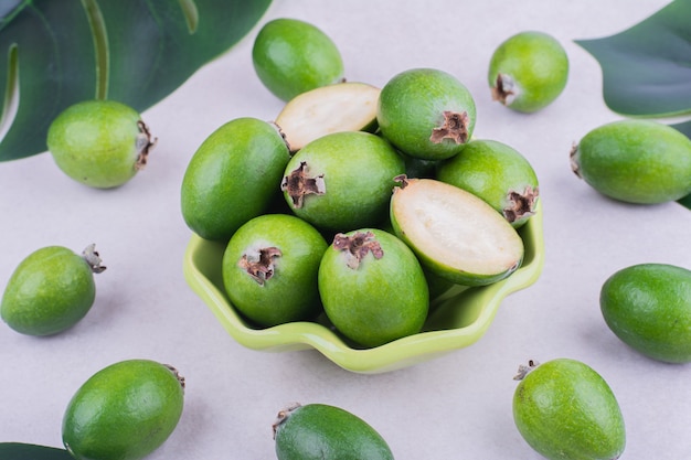 Feijoas en una taza verde sobre superficie gris