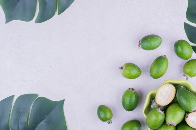 Feijoas en una taza verde sobre superficie gris