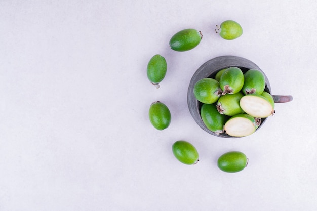 Feijoas verdes en una olla metálica sobre superficie gris