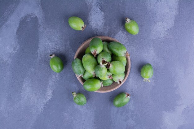 Foto gratuita feijoas verdes en una taza de madera en azul.