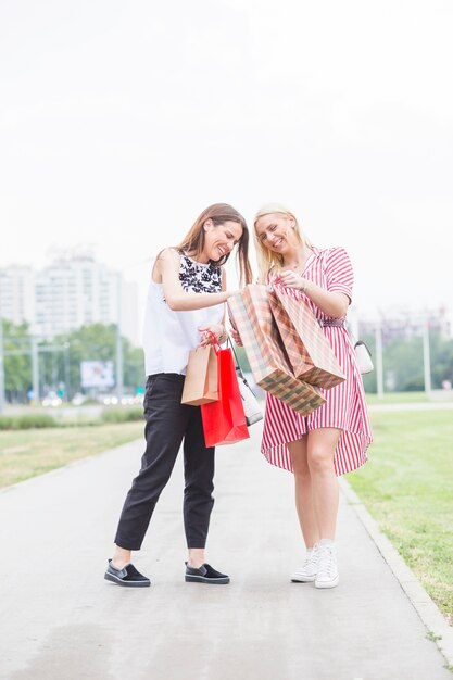 Felices amigas mirando en los bolsos de compras