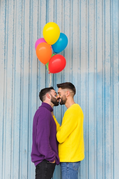 Felices amores gay besándose y sosteniendo globos