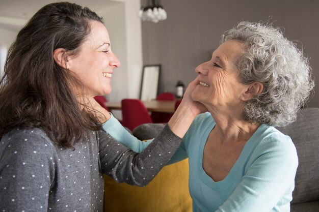 Felices anciana madre e hija tocando caras de unos a otros