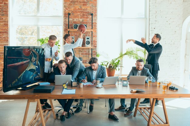 Felices colegas despreocupados que se divierten en la oficina mientras sus compañeros de trabajo trabajan duro y muy concentrados.