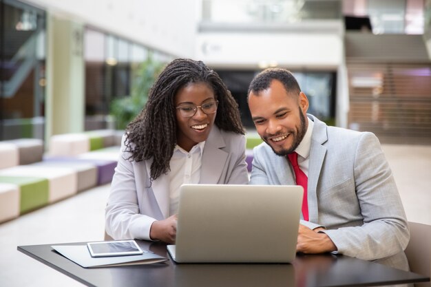 Felices colegas emocionados usando laptop para videollamada