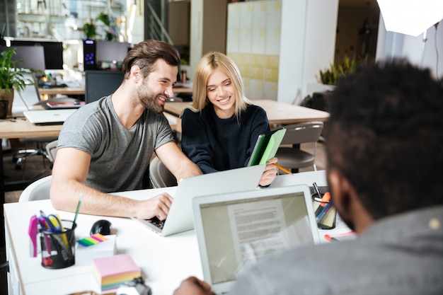 Felices colegas jóvenes sentados en la oficina de coworking