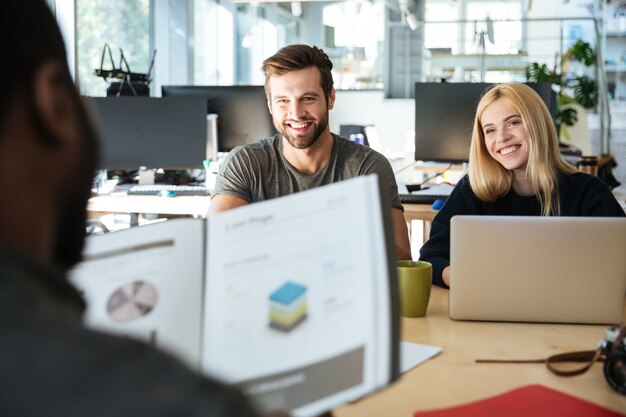 Felices colegas jóvenes sentados en la oficina de coworking