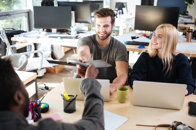 Felices colegas jóvenes sentados en la oficina de coworking