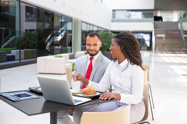 Felices colegas de negocios desayunando en la cafetería