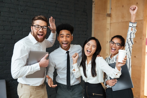 Foto gratuita felices colegas de negocios jóvenes emocionados hacen gesto ganador.