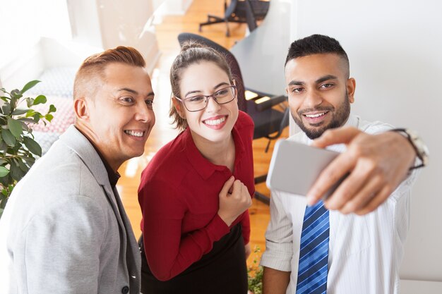 Felices compañeros de oficina exitosa tomando selfie