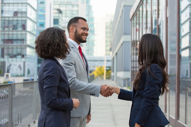 Foto gratuita felices empresarios positivos reunidos afuera