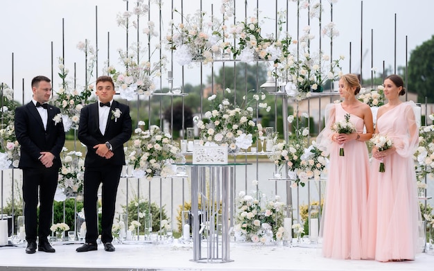 Felices fritos de novias cerca del arco decorativo de la boda