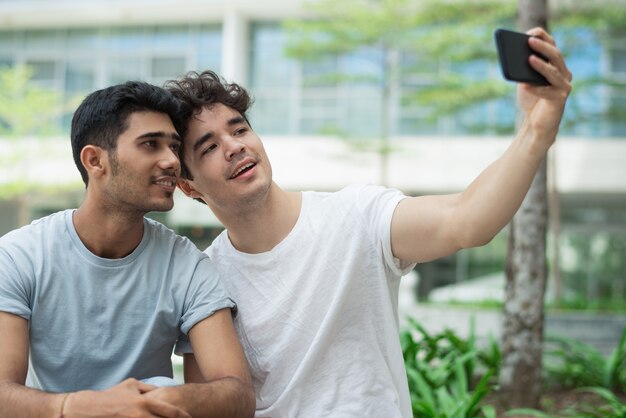 Felices gays interraciales posando para una linda selfie en la ciudad